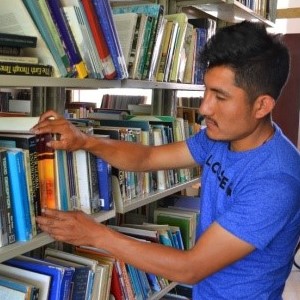 Alumno revisando libros en nuestra estantería abierta